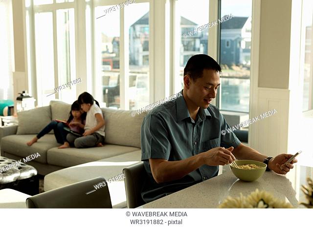 Father having breakfast and girls using digital tablet
