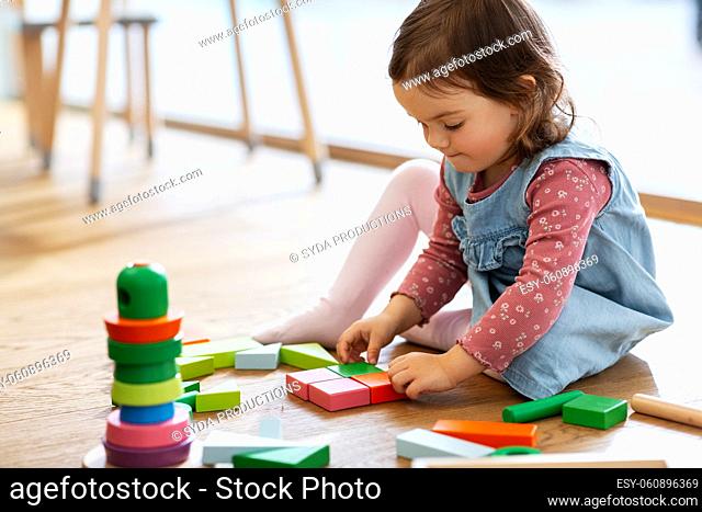 happy baby girl playing with toy blocks at home