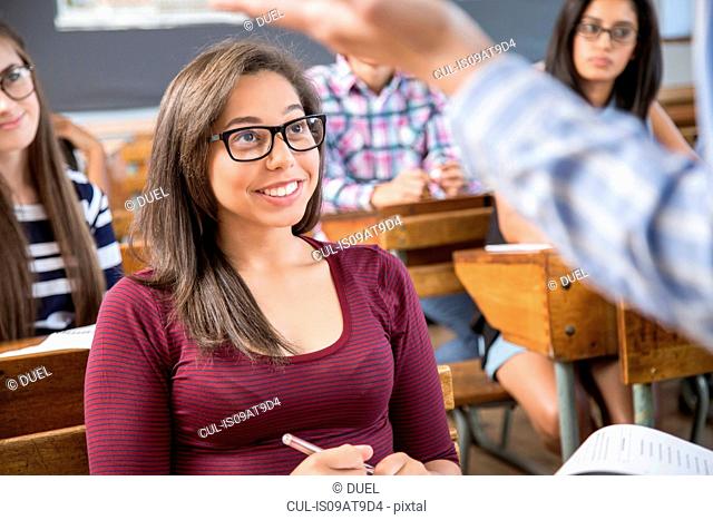 Female student listening to teacher in classroom