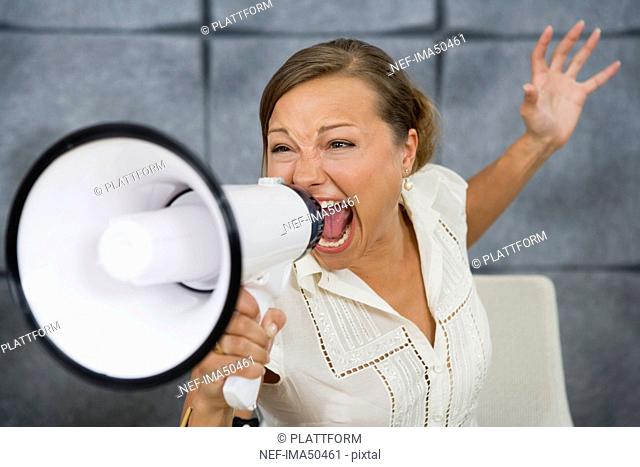 A woman yelling in a megaphone in an office, Sweden