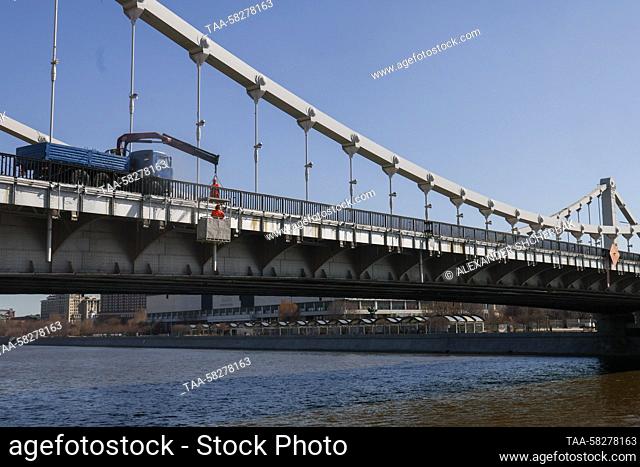 RUSSIA, MOSCOW - APRIL 7, 2023: A worker uses a high pressure water jet to clean the surface of Krymsky Bridge in spring. Alexander Shcherbak/TASS