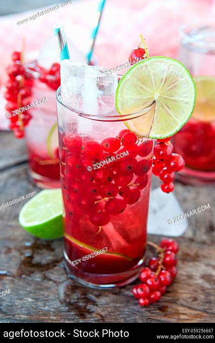 Hohes Glas mit Cocktail mit frischen roten Johannisbeeren und Limette