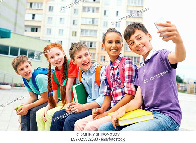 Modern school learners making selfie outside