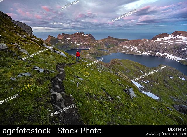 Sunset with dramatic clouds, hiker on hike to Hermannsdalstinden, lakes Krokvatnet and Tennesvatnet, mountains, Moskenesøya, Lofoten, Nordland, Norway, Europe