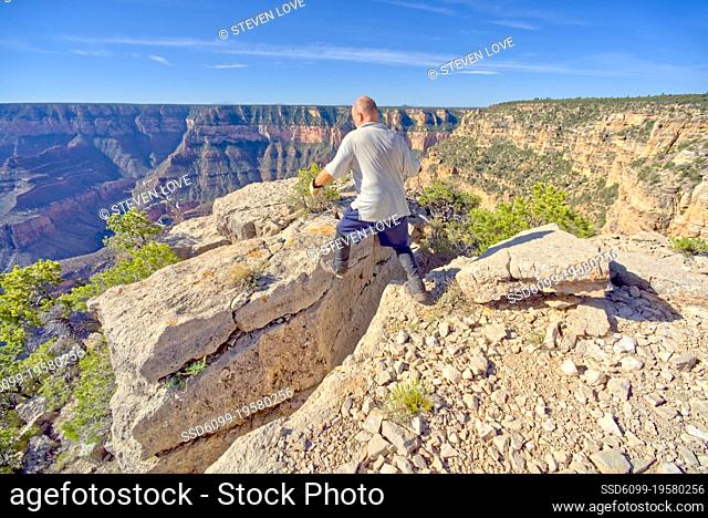 A man jumping across a cliff crevice east of Shoshone Point at Grand Canyon Arizona