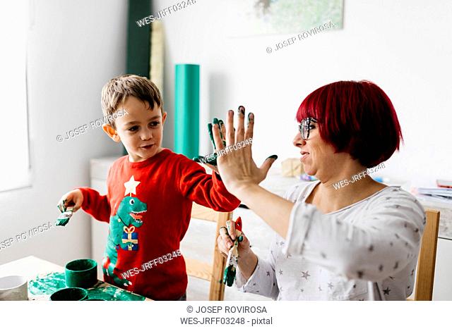 Happy mother and son high fiving while doing crafts at home