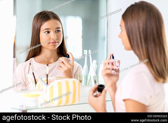 teenage girl spraying perfume at bathroom