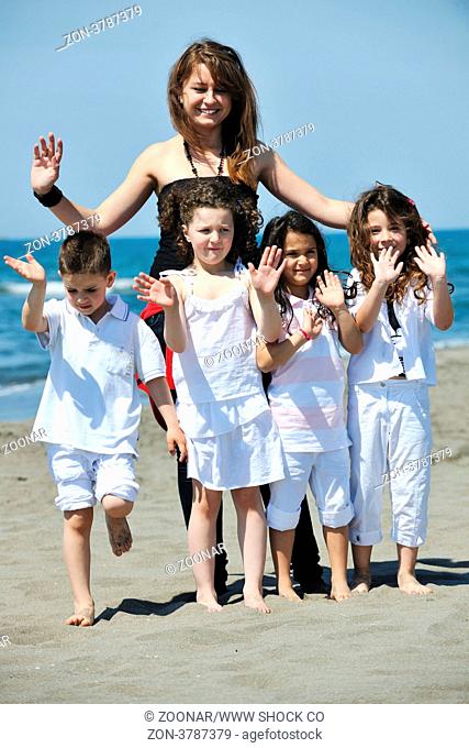 group portrait of happy childrens with young female teacher on beach