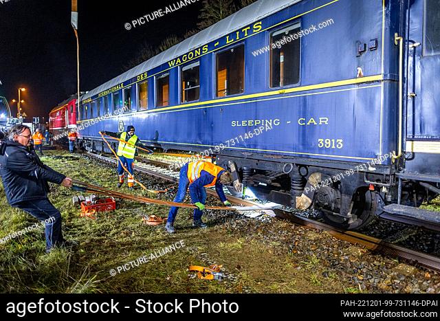 30 November 2022, Mecklenburg-Western Pomerania, Gadebusch: Holger Hempel (l), the proud new owner, pulls a sling under the sleeping car from the legendary...