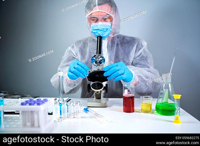 Pharmaceutical manufacturers developing viral medicines by inventing best ingredient. Scientist wearing personal protective equipment with face mask watching...