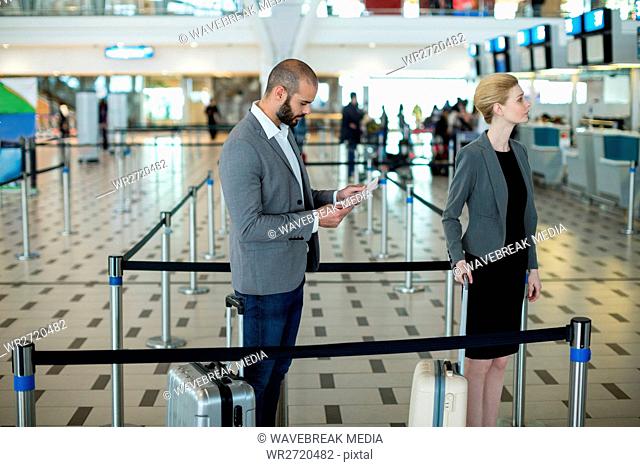 Businesspeople waiting in queue at a check-in counter with luggage