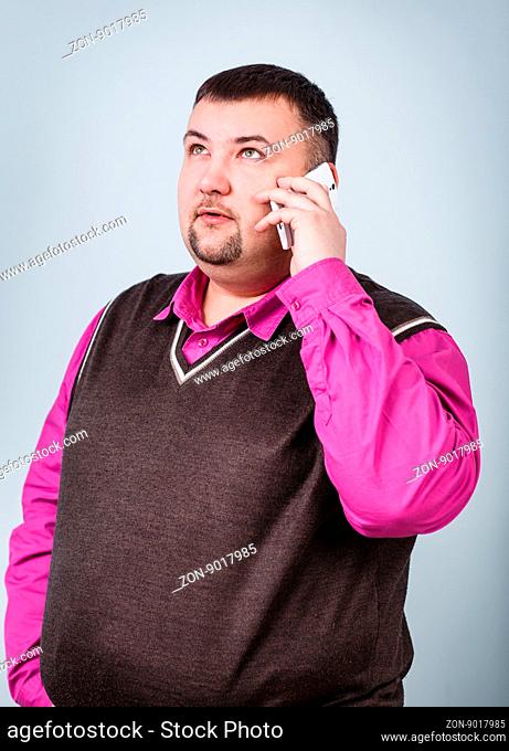Businessman with overweight speaks on the phone on the gray background