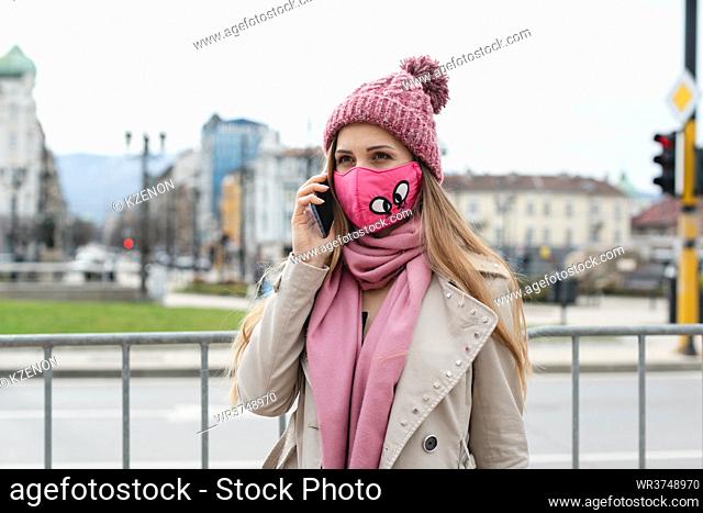 Woman with fashion mask using her phone in city