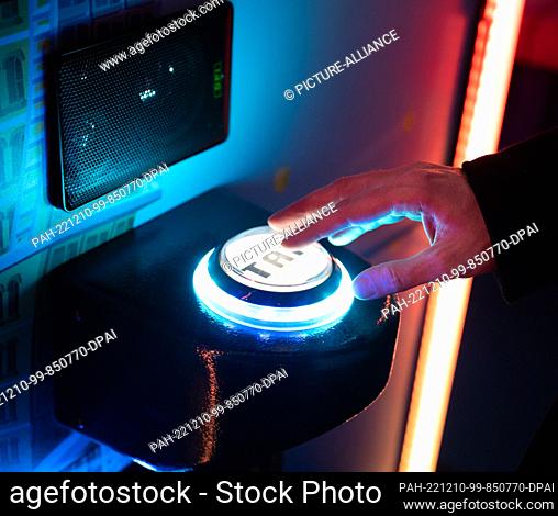 08 December 2022, Berlin: A young man's hand touches a game button on a slot machine in the ""Gamestate"" arcade on Potsdamer Platz