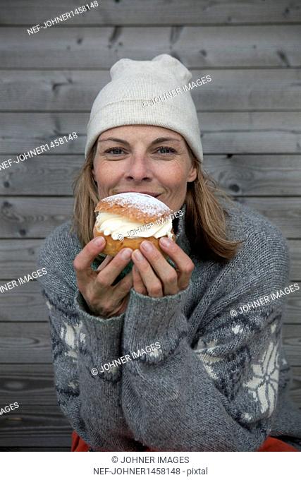 Portrait of woman wearing warm clothing eating cake