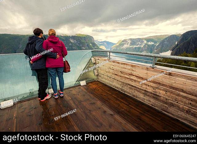 Tourist couple enjoying fjord view Aurlandsfjord landscape from Stegastein viewing point. Norway Scandinavia. National tourist route Aurlandsfjellet