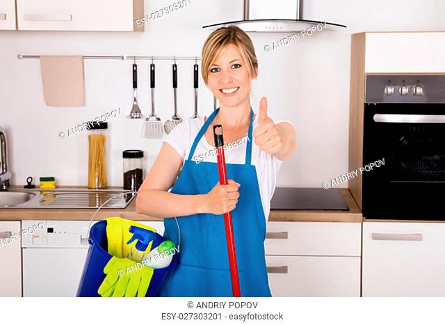 Cleaning Service Professional Housemaid Holding Gloves And Equipment In Kitchen At Home Showing Thumbs Up