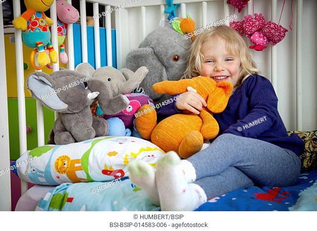 3-year-old girl on her bed with her soft toys
