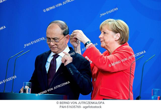 German Chancellor Angela Merkel (CDU, R) helps the President of Myanmar, Thein Sein, to put on his headphones at the beginning of a press conference in the...