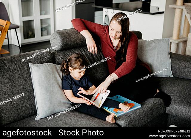 Mother with daughter reading book