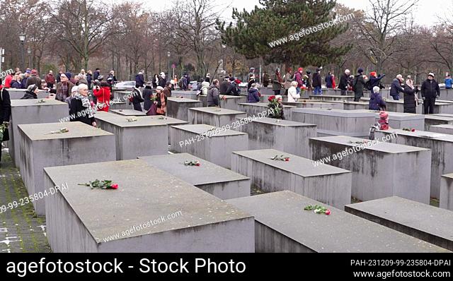 09 December 2023, Berlin: People gather at the Holocaust memorial and lay red roses on the stelae as a sign against anti-Semitism