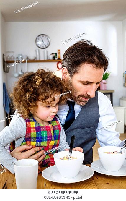 Man and daughter having cereal breakfast in kitchen