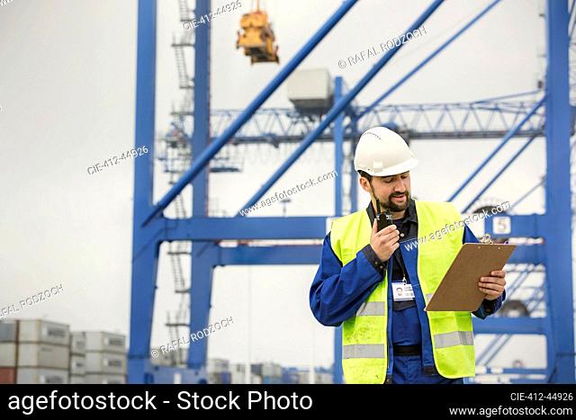 Dock worker with walkie-talkie and clipboard at shipyard