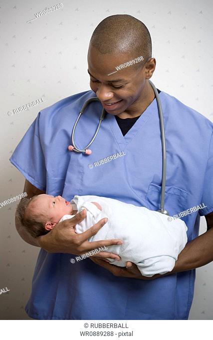 Male doctor carrying a new born baby