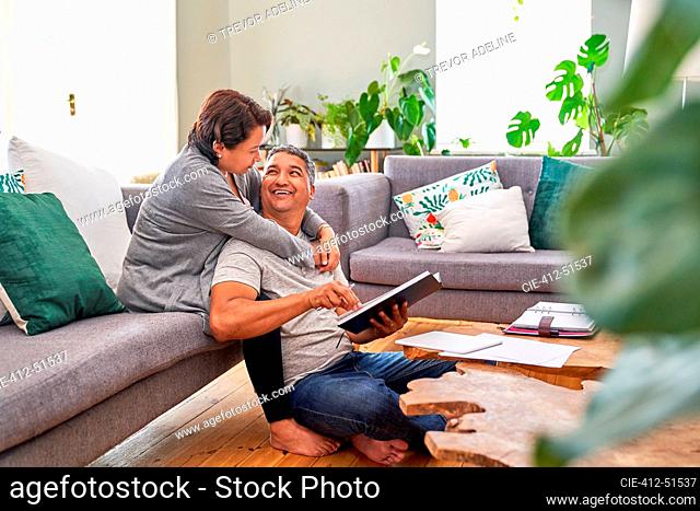 Affectionate mature couple reading and talking in living room