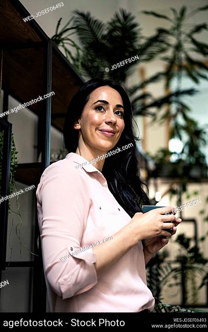 Smiling businesswoman having coffee in coworking office