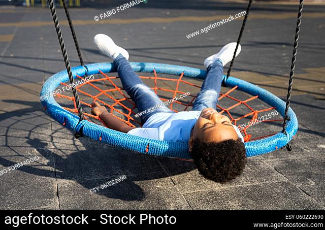 Beautiful happy african american family bonding at the park - Black family having fun outdoors, cute boy playing at the swing