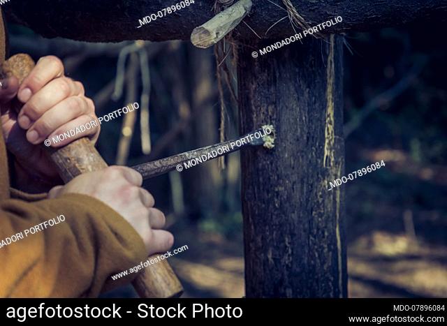 Lombards 6th/7th Century, Italy, Friuli Venezia Giulia:daily duties. Making holes with a spoon bit hand drill in the load-bearing poles of the Grubenhaus (hut)...