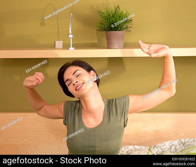 Happy woman waking up stretching and smiling in morning with closed eyes