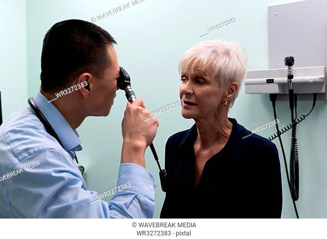 Young Asian male doctor examining a senior patient in the clinic