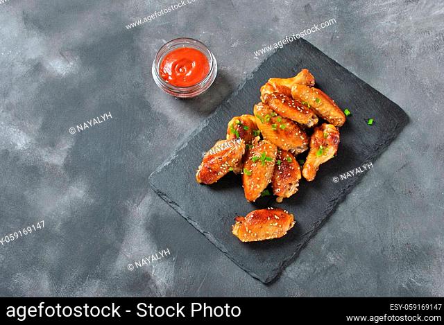 Fried barbecue chicken wings close up on wooden tray shot with selective focus