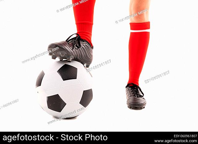 Low section of caucasian young female player with foot on soccer ball against white background