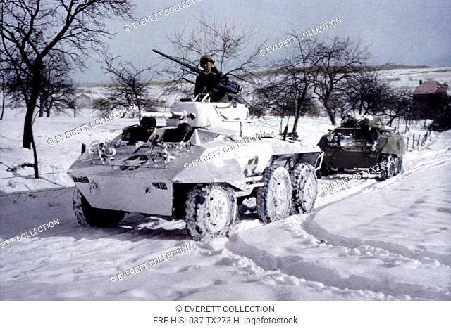 Camouflaged light armored vehicle is contrasts with the following brown vehicle. Dec. 12, 1944 through Jan.25, 1945. Battle of the Bulge, World War 2