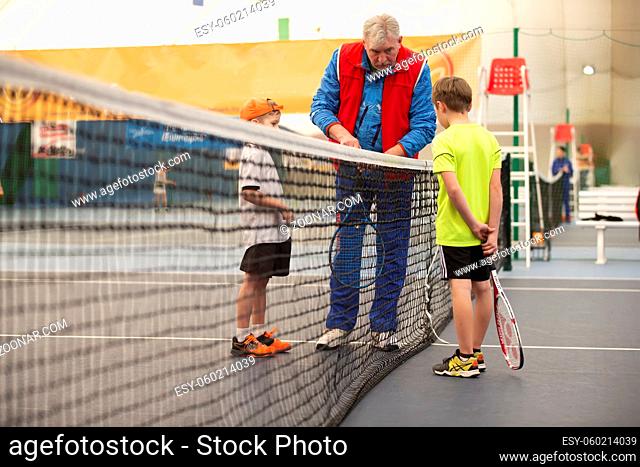 April 01, 2021. Belarus, the city of Gomil. Children's competitions in big tennis. Two children with tennis rackets and a judge on the tennis court