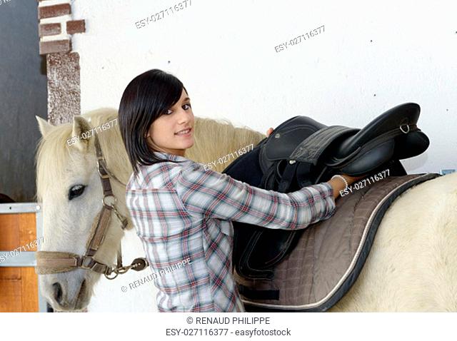 Beautiful young brunette girl and white horse in the stale