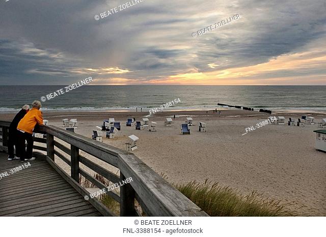 Two women on a wooden footbridge at the beach of Kampen, Sylt, Germany
