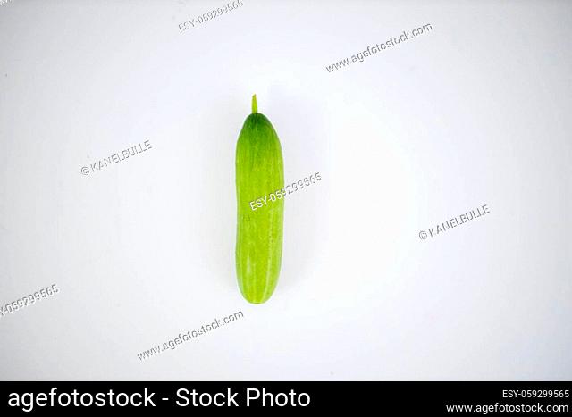 Cucumber isolated lying on white table. Above view of fresh vegetable on white surface. Healthy meal preparation