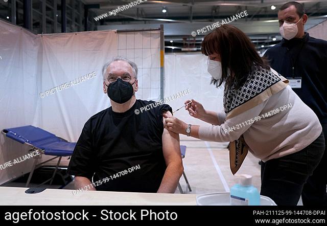 25 November 2021, Saxony-Anhalt, Magdeburg: Minister President Reiner Haseloff (CDU) receives his booster vaccination from doctor Susanne Göbel at the...