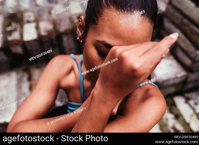Young woman covering face with hands