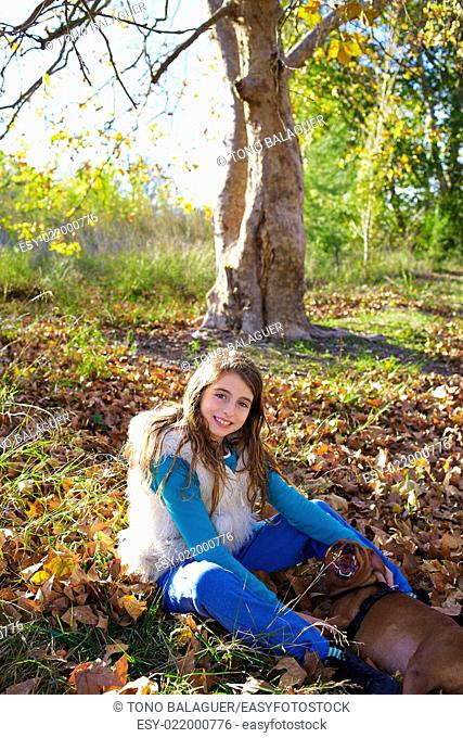 Autumn kid girl with pet dog relaxed in fall forest in Parc de Turia Valencia Spain