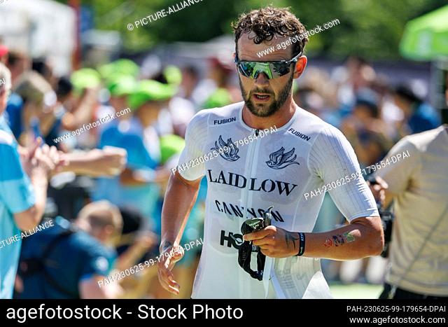 25 June 2023, Bavaria, Roth: Sam Laidlow, triathlete from France, leaves the transition zone from the bike leg to the run leg at the Datev Challenge Roth