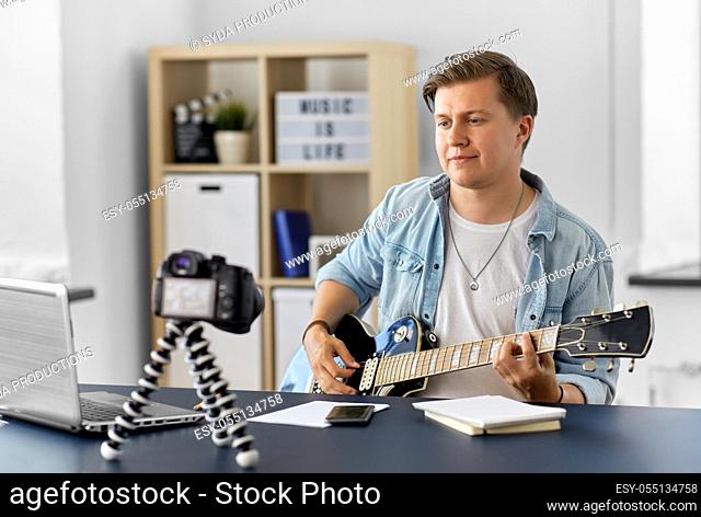 man or blogger with camera playing guitar at home