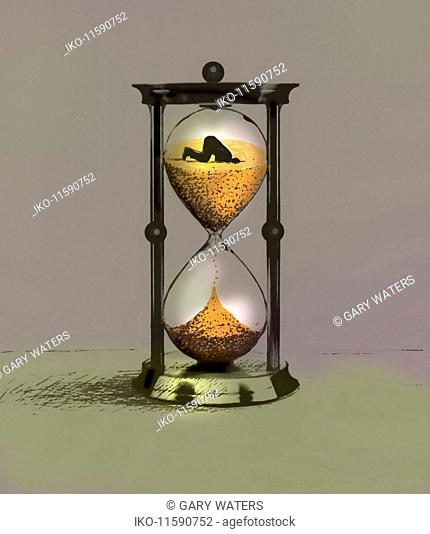 Man burying head in the sand of time running out of hourglass