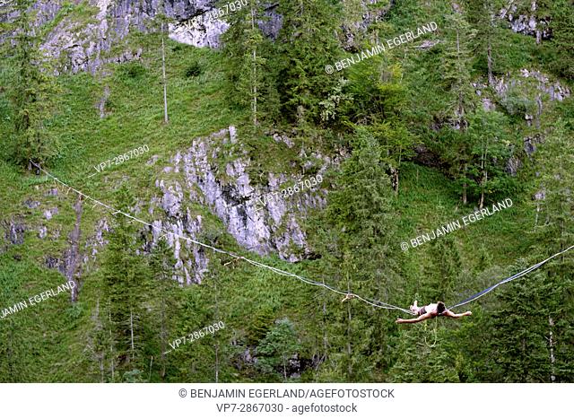 young man relaxing on highline slackline in nature above valley, in south of Germany, Bavaria, near border to Austria