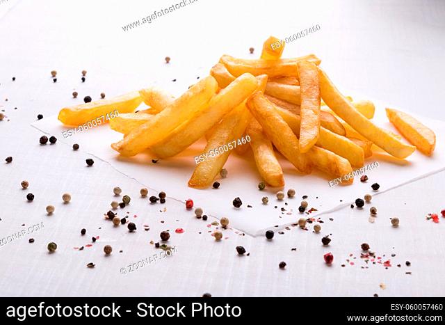 fresh yellow fries on white table with peppercorn seasoning