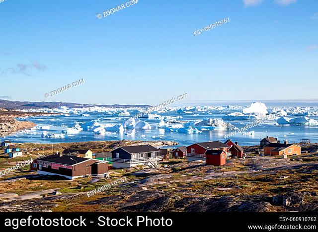 Rodebay, Greenland - July 09, 2018: Colorful wooden houses with icebergs in the background. Rodebay, also known as Oqaatsut is a fishing settlement north of...